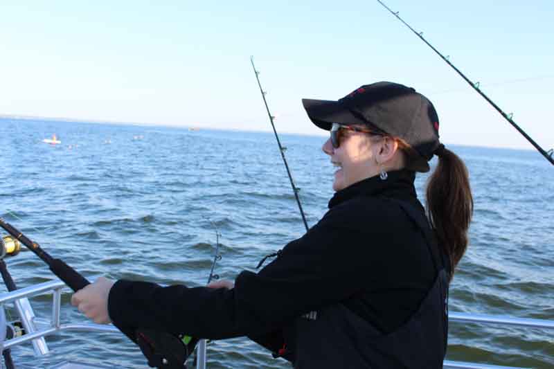 happy fisherwoman reels up a fish