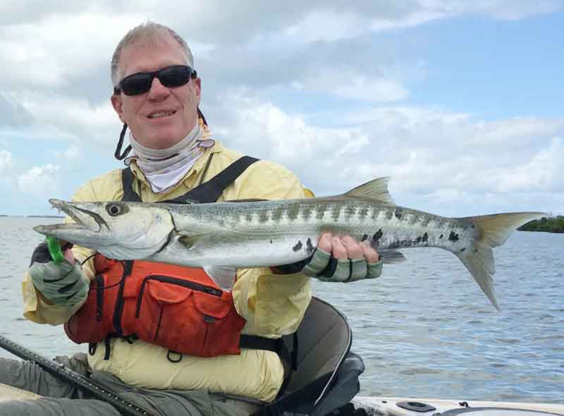 holding up a barracuda caught on a kayak