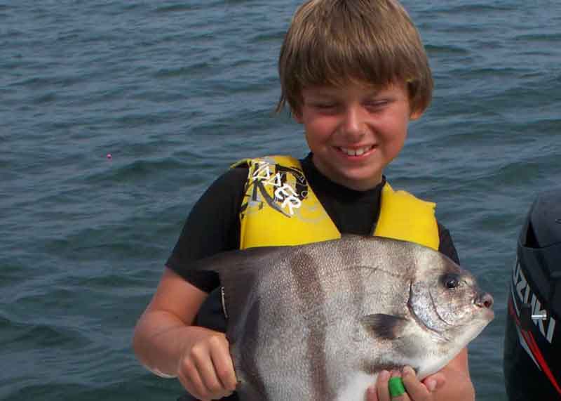 kid holding up a spadefish
